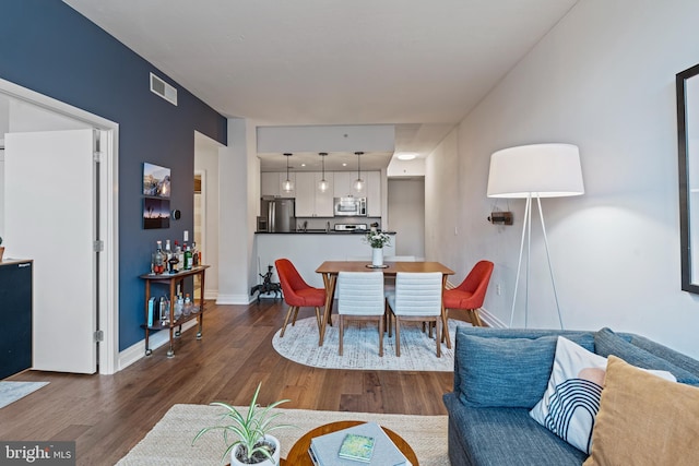 dining area with dark wood-style floors, visible vents, and baseboards