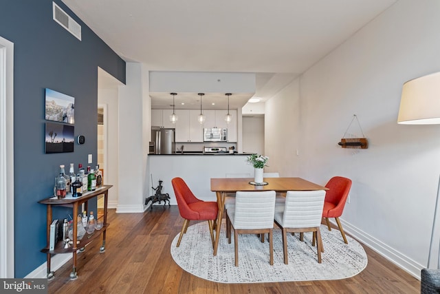 dining room featuring dark wood-style floors, visible vents, and baseboards