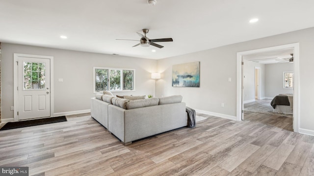 living room with recessed lighting, baseboards, and light wood finished floors