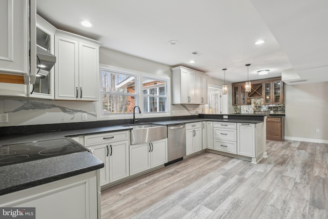 kitchen with decorative backsplash, light wood-style flooring, a peninsula, a sink, and stainless steel dishwasher