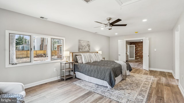 bedroom featuring attic access, visible vents, baseboards, and wood finished floors