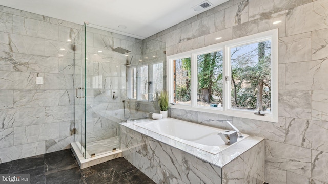 full bath featuring a garden tub, a marble finish shower, visible vents, and tile walls