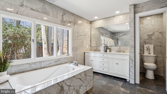 bathroom featuring double vanity, tile walls, a sink, and a bath