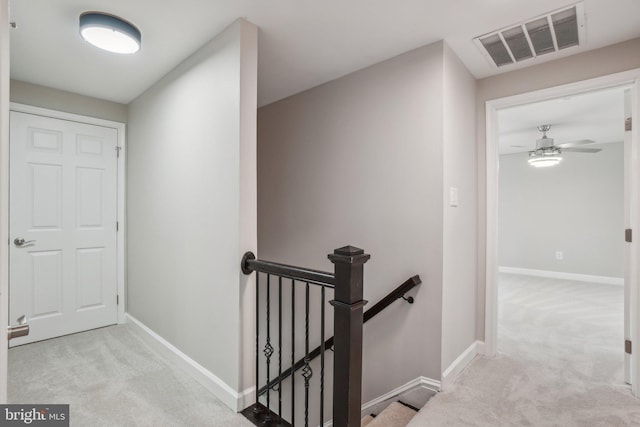 corridor featuring carpet floors, baseboards, visible vents, and an upstairs landing