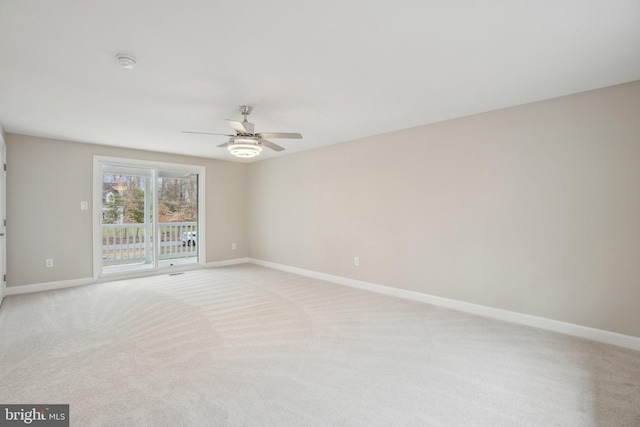 spare room with a ceiling fan, light carpet, and baseboards