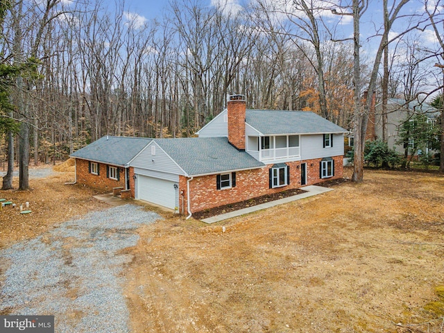 view of front of home with brick siding, roof with shingles, a chimney, an attached garage, and driveway