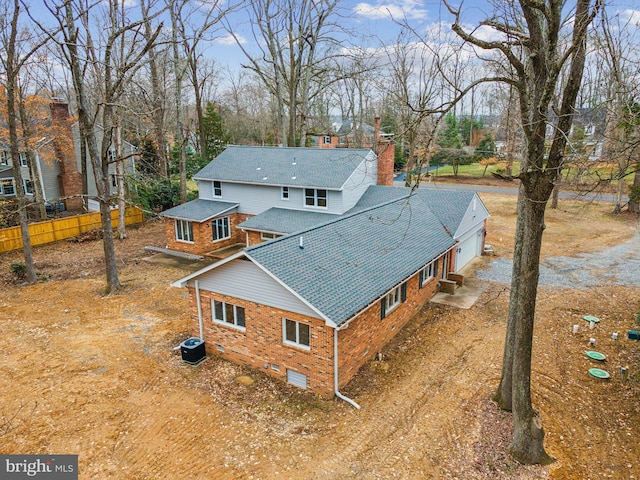 back of property with brick siding, dirt driveway, central AC unit, crawl space, and fence