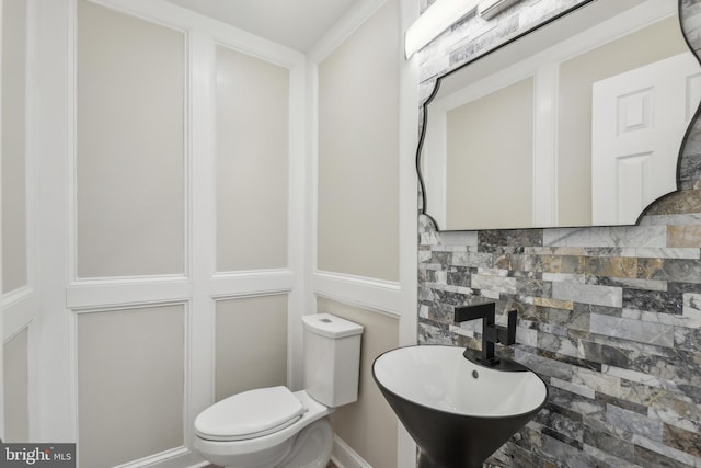 bathroom featuring tasteful backsplash, a sink, and toilet