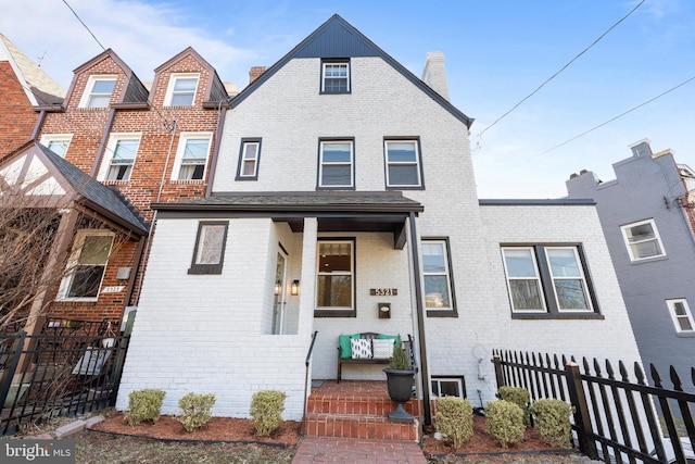 townhome / multi-family property with brick siding, a chimney, and fence