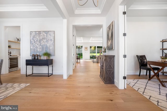 hallway featuring a tray ceiling, beverage cooler, baseboards, and light wood finished floors