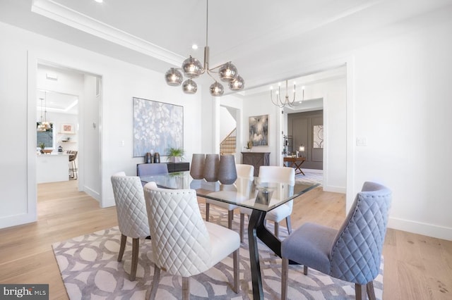 dining area featuring light wood finished floors, stairs, a chandelier, and ornamental molding