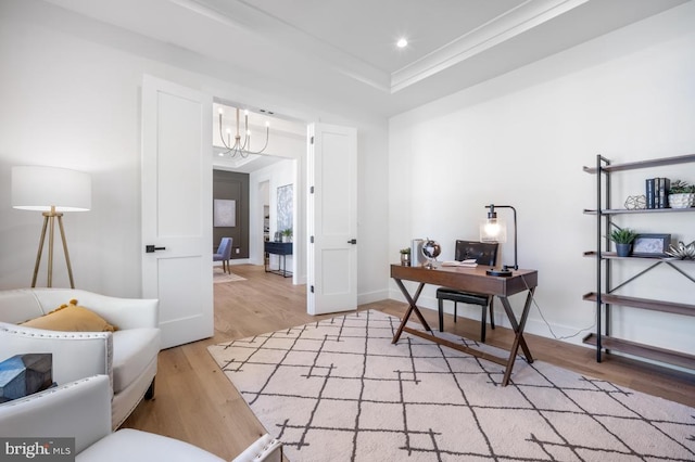 office space with a chandelier, recessed lighting, ornamental molding, light wood-type flooring, and a tray ceiling