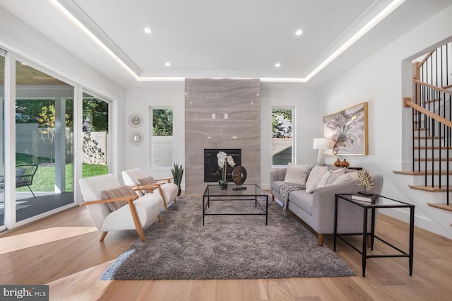 living room featuring a tray ceiling, plenty of natural light, and stairs