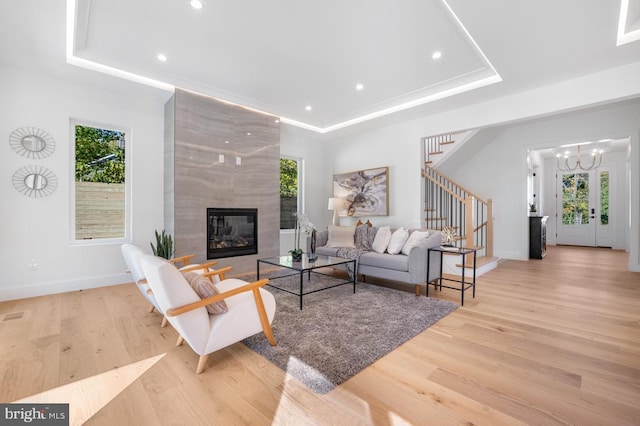 living room with stairway, a tray ceiling, and wood finished floors