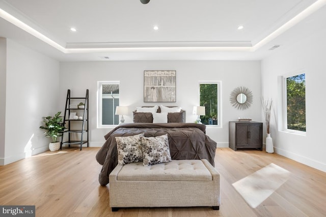 bedroom with a tray ceiling, recessed lighting, wood finished floors, and baseboards