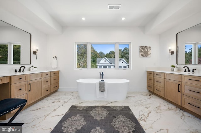 bathroom with marble finish floor, recessed lighting, two vanities, and a soaking tub