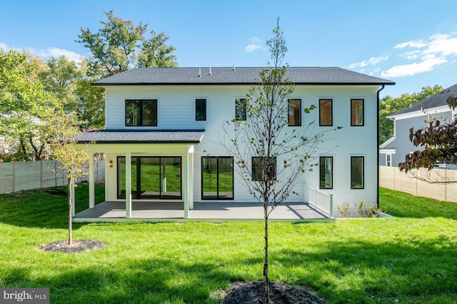 rear view of property featuring fence, a patio, and a lawn