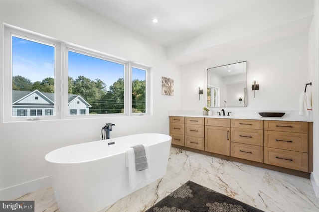 full bath with marble finish floor, recessed lighting, a freestanding bath, vanity, and baseboards