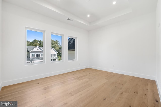 spare room with recessed lighting, visible vents, baseboards, light wood-type flooring, and a raised ceiling