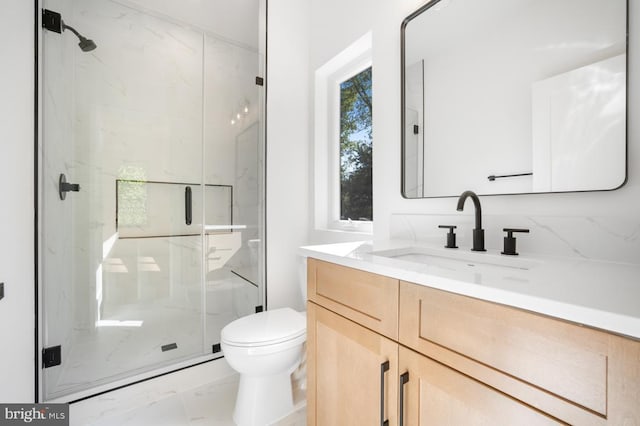 full bathroom featuring marble finish floor, toilet, vanity, and a marble finish shower