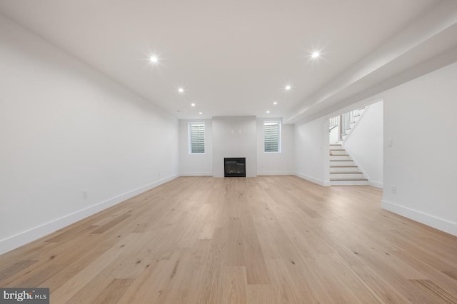 unfurnished living room with a fireplace, recessed lighting, light wood-style flooring, stairway, and baseboards