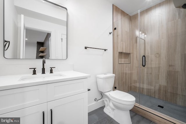 bathroom with a stall shower, vanity, toilet, and baseboards