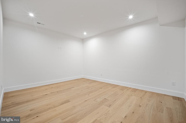 empty room featuring baseboards, visible vents, and wood finished floors