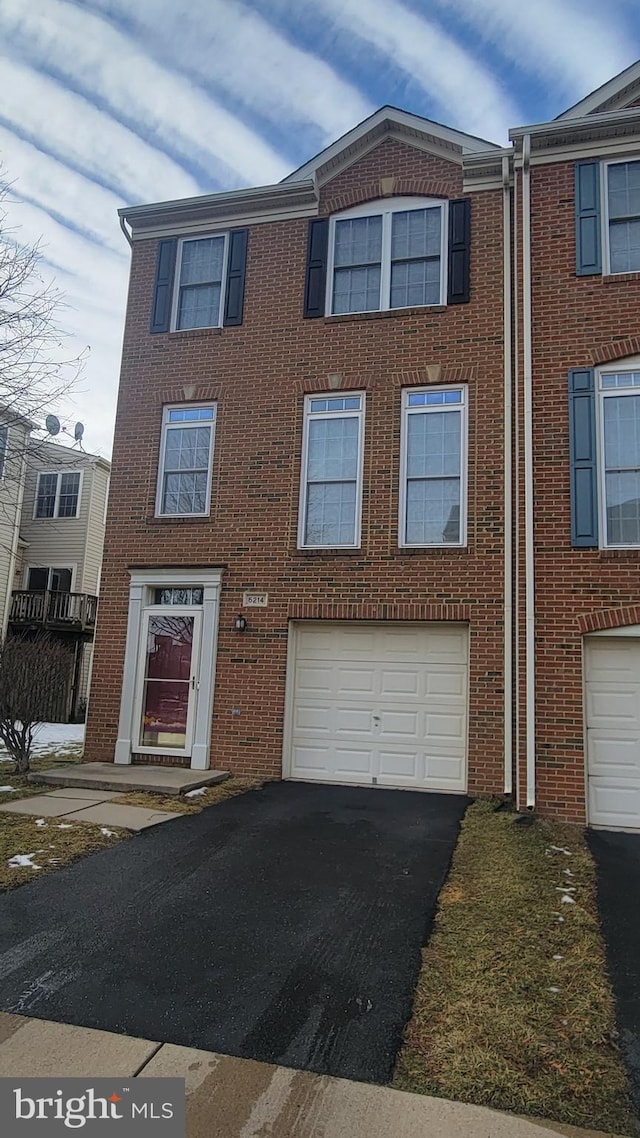 townhome / multi-family property with aphalt driveway, a garage, and brick siding