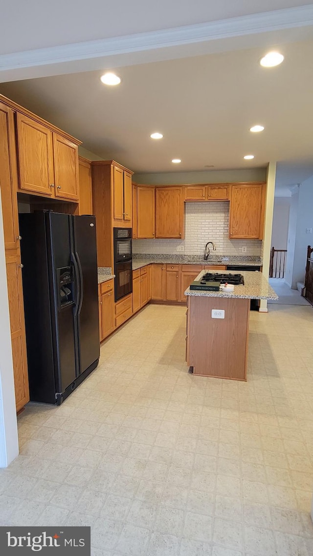 kitchen with light stone counters, light floors, recessed lighting, backsplash, and black appliances