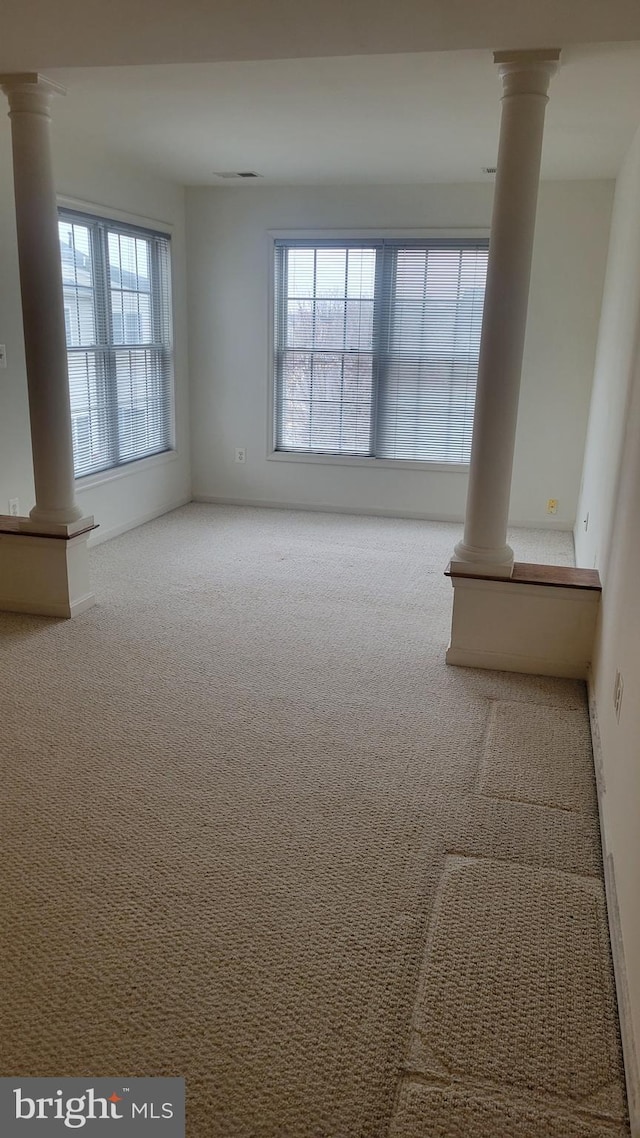 carpeted empty room with plenty of natural light and ornate columns