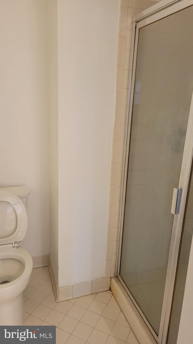 full bathroom with toilet, a shower stall, baseboards, and tile patterned flooring