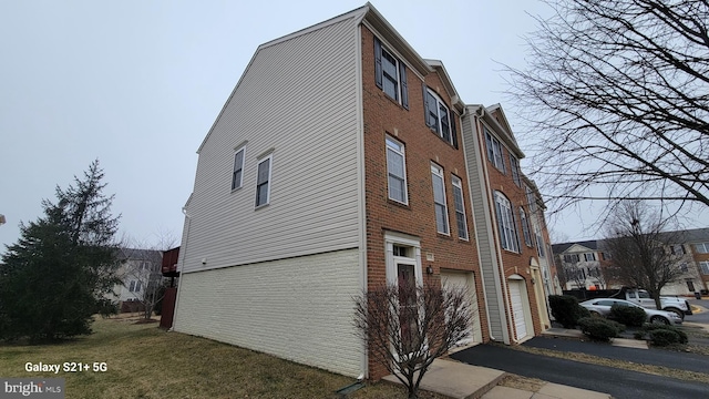 view of property exterior featuring a garage, brick siding, and aphalt driveway