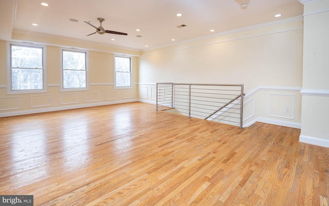 empty room with crown molding, a decorative wall, wood finished floors, and recessed lighting