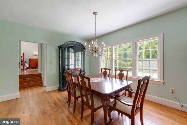 dining space with baseboards, a notable chandelier, and light wood-style floors