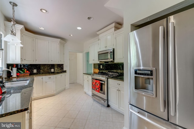 kitchen with tasteful backsplash, appliances with stainless steel finishes, white cabinets, and a sink