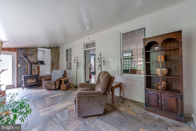 sitting room featuring a wood stove and stone tile flooring