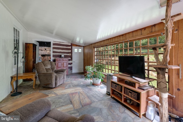 living room with stone finish floor, vaulted ceiling, and wood walls