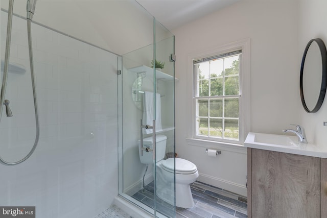 bathroom with a stall shower, baseboards, toilet, wood tiled floor, and vanity