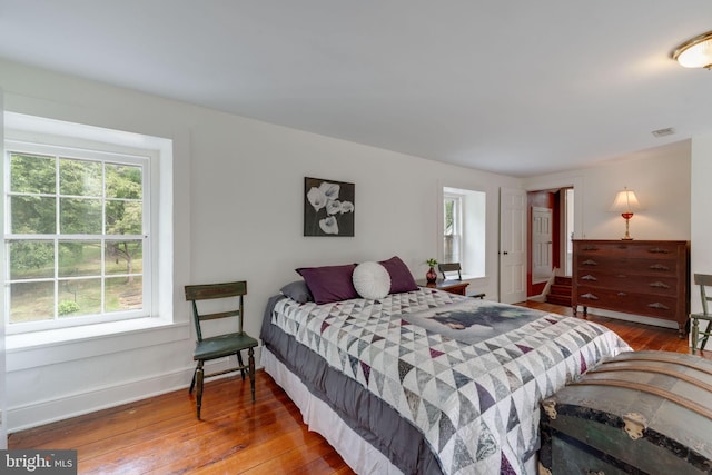 bedroom featuring wood-type flooring, visible vents, and baseboards