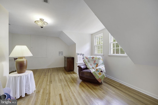 living area with baseboards, visible vents, and hardwood / wood-style floors