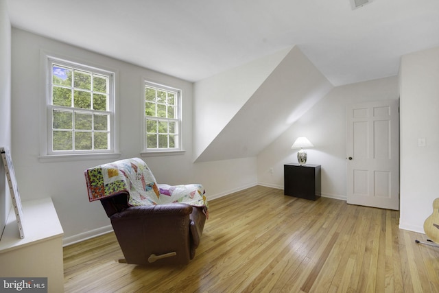 living area featuring hardwood / wood-style flooring, baseboards, and vaulted ceiling