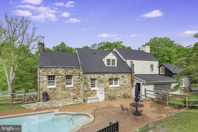 rear view of house with a gate, a chimney, an outdoor pool, and a patio