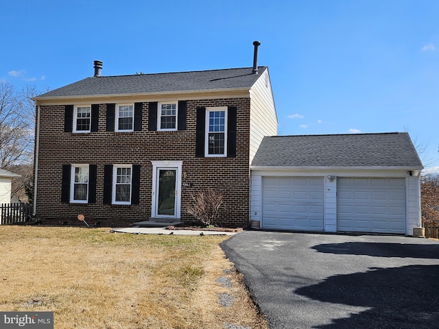 colonial house featuring a garage, a front lawn, brick siding, and driveway