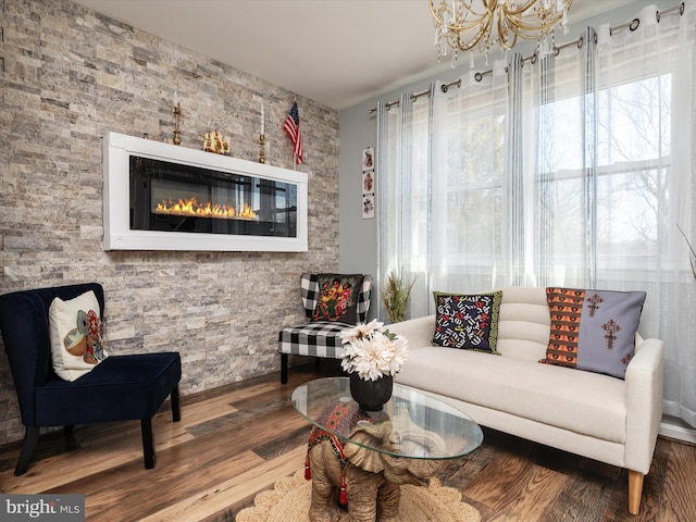 living room featuring a glass covered fireplace, an inviting chandelier, and wood finished floors