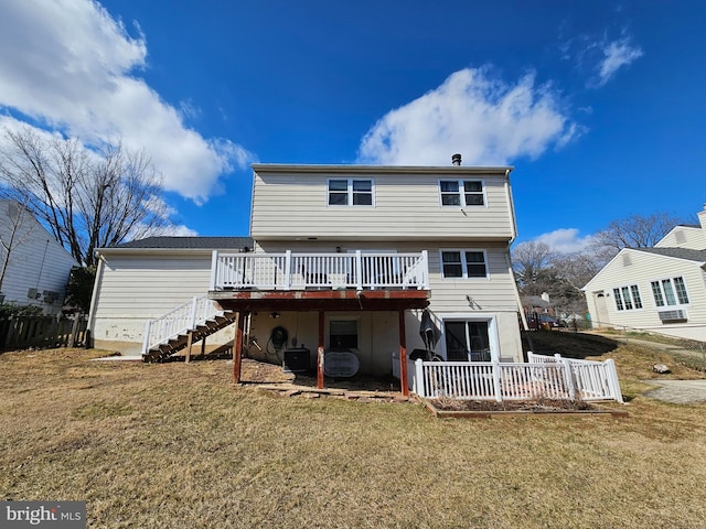 rear view of house with stairway, a wooden deck, a yard, and fence