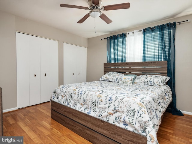 bedroom with ceiling fan, baseboards, multiple closets, and wood finished floors