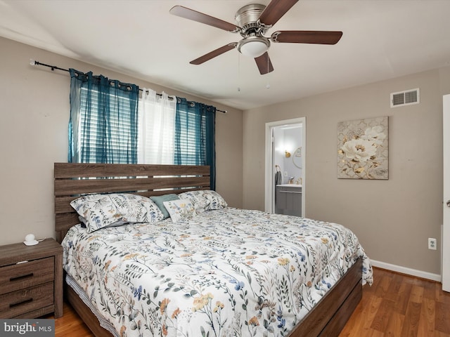 bedroom with a ceiling fan, wood finished floors, visible vents, baseboards, and ensuite bathroom