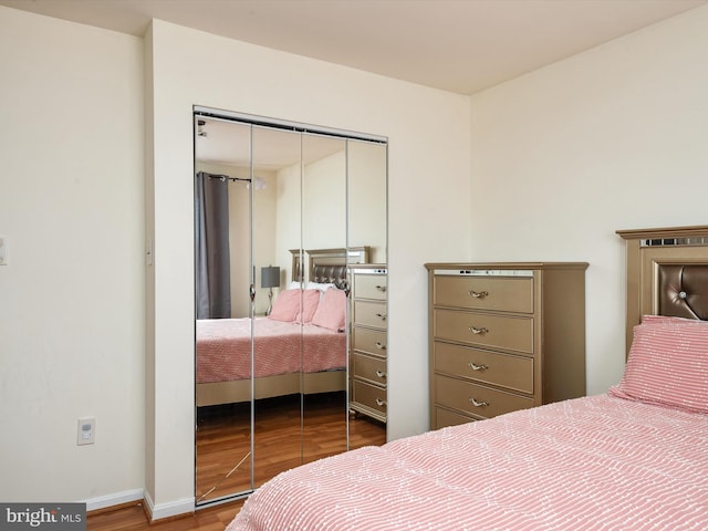 bedroom with a closet, baseboards, and wood finished floors