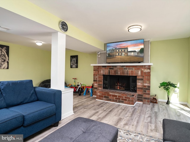 living room with a fireplace, wood finished floors, visible vents, and baseboards