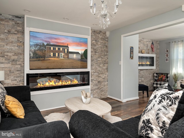 living area with a chandelier, a glass covered fireplace, baseboards, and wood finished floors